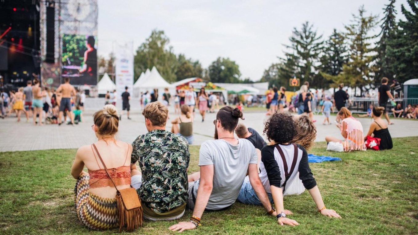 Guests seated on grass at an open-air festival in Dubai with tents needing outdoor cooling