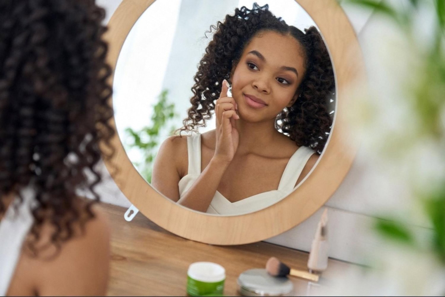 Woman applying serum in front of a mirror, showing an evening UAE skincare step